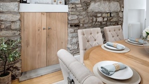 Comedor con pared de piedra, armarios de madera y una mesa redonda para cuatro comensales.