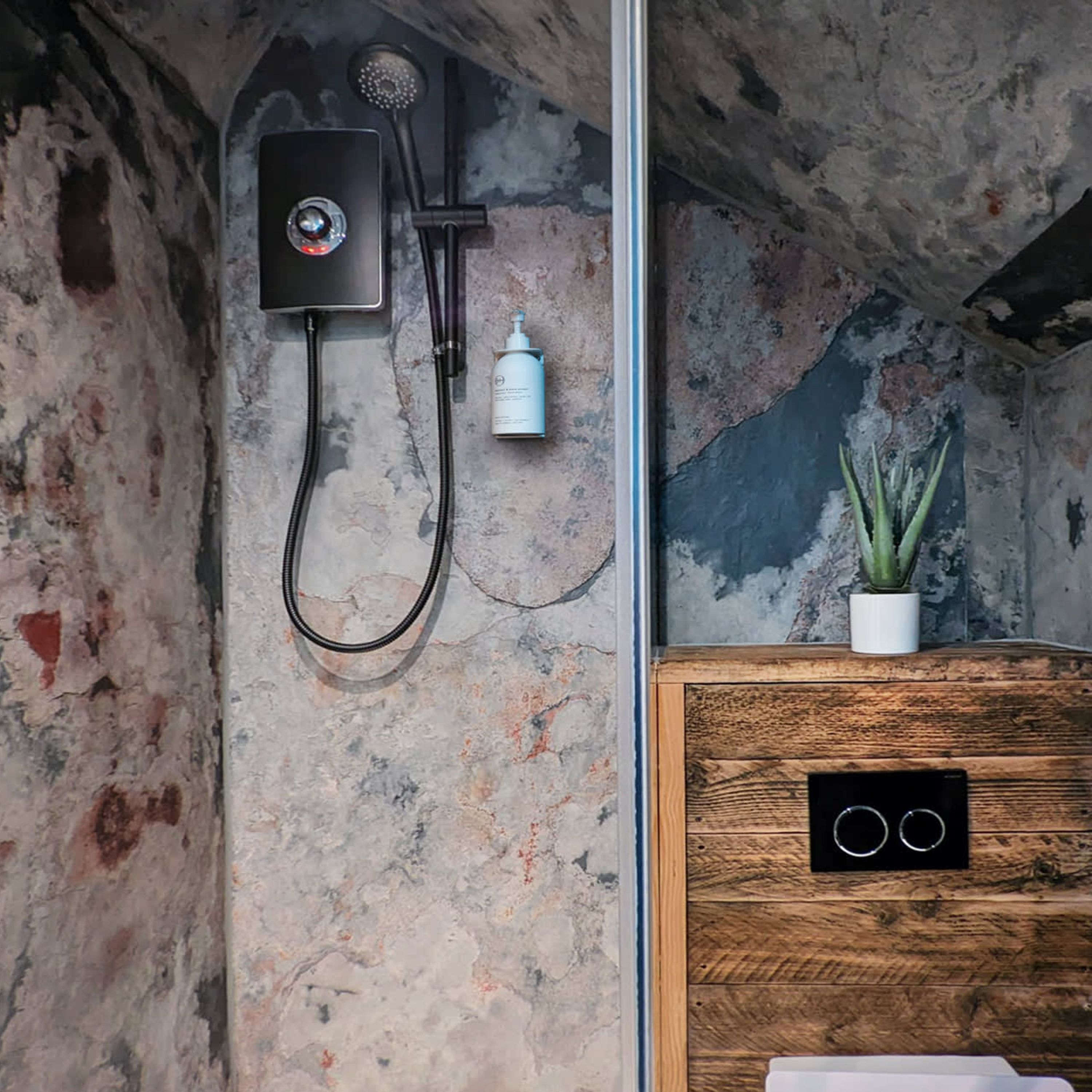 Un baño con ducha, una botella blanca y un mueble de madera.