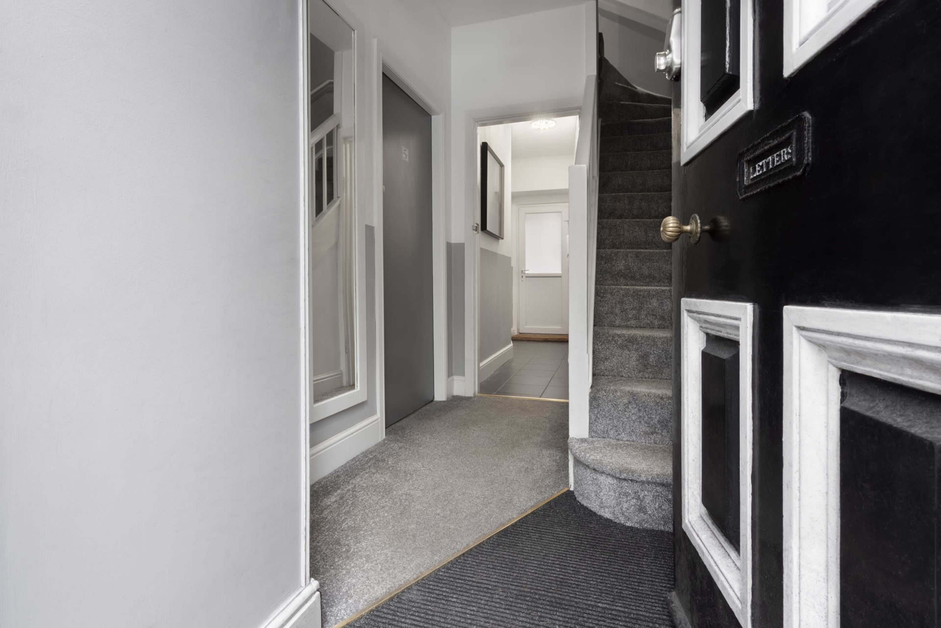 A hallway with a carpeted floor, a door labeled "LETTERS," and a staircase leading to another room.