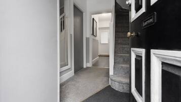 Un pasillo con piso alfombrado, una puerta con la leyenda 'LETTERS' y una escalera que conduce a otra habitación.