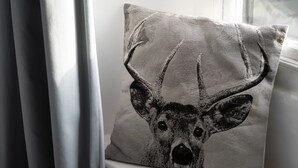 Un coussin orné d’un motif de cerf, posé sur un rebord de fenêtre.