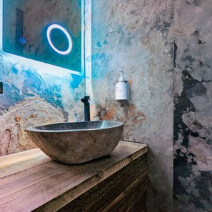 A rustic bathroom with a large, round vessel sink on a wooden vanity, a neon-lit mirror, and a white soap dispenser on the wall. - Windermere Central Hotel - Room 2 (Windermere)