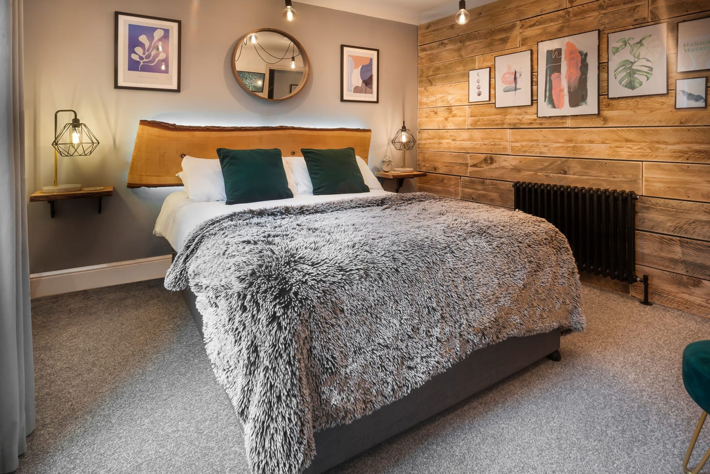 Un dormitorio moderno con una cama grande, un panel de pared de madera y obras de arte enmarcadas.