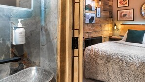 A bathroom with a stone sink, a hand soap dispenser, and a wooden-framed mirror. - Windermere Central Hotel - Room 4 (Windermere)