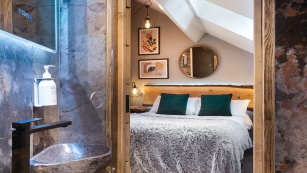A rustic bathroom with a stone basin, wooden shelves, and a towel dispenser. - Windermere Central Hotel - Room 4 (Windermere)