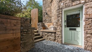 A stone building with a wooden door and steps leading to a bench. - Eden Escape - Comfy Apartment Quiet Neighbourhood (Kendal)