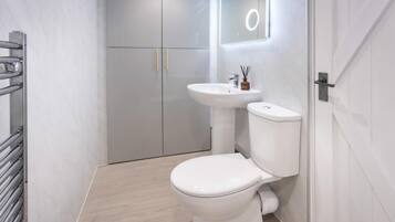 A modern bathroom with a white toilet, a sink, and a mirror.