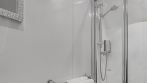 A modern bathroom with a glass-enclosed shower, a white sink, and a towel rack. - Windermere Central Hotel - Room 6 (Windermere)