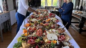 A long table filled with an assortment of cheeses, fruits, and meats, set in a room with large windows and a chandelier. - Lyth Valley Country House - 9 Rooms (Kendal)