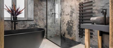 A modern bathroom with a freestanding bathtub, a glass-enclosed shower, and a wooden towel rack.