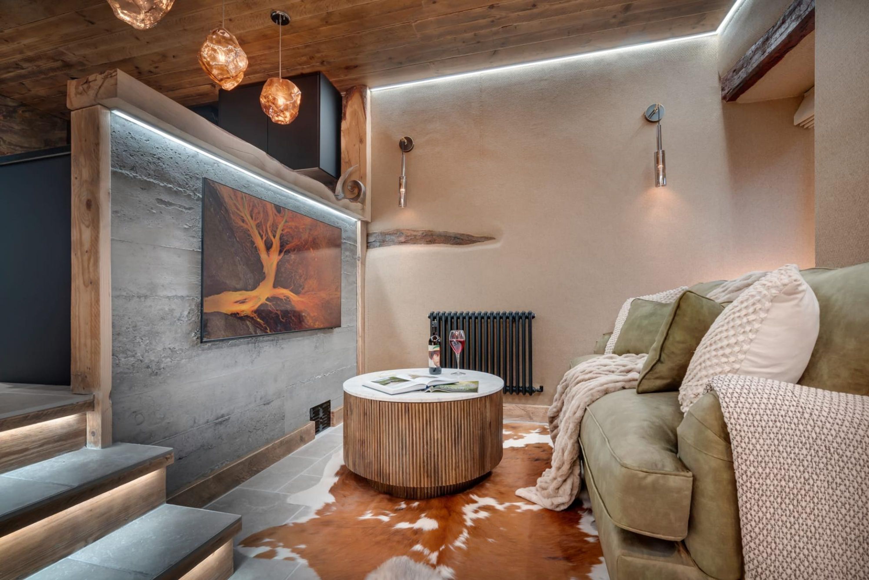Un salon moderne avec une table basse ronde en bois, un canapé vert et un tapis en peau de vache.