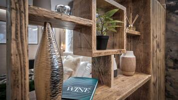 A wooden shelf with a book titled 'The World Atlas of Wine', a potted plant, and a vase.