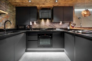 Una cocina moderna con armarios oscuros, horno integrado y salpicadero de mármol.