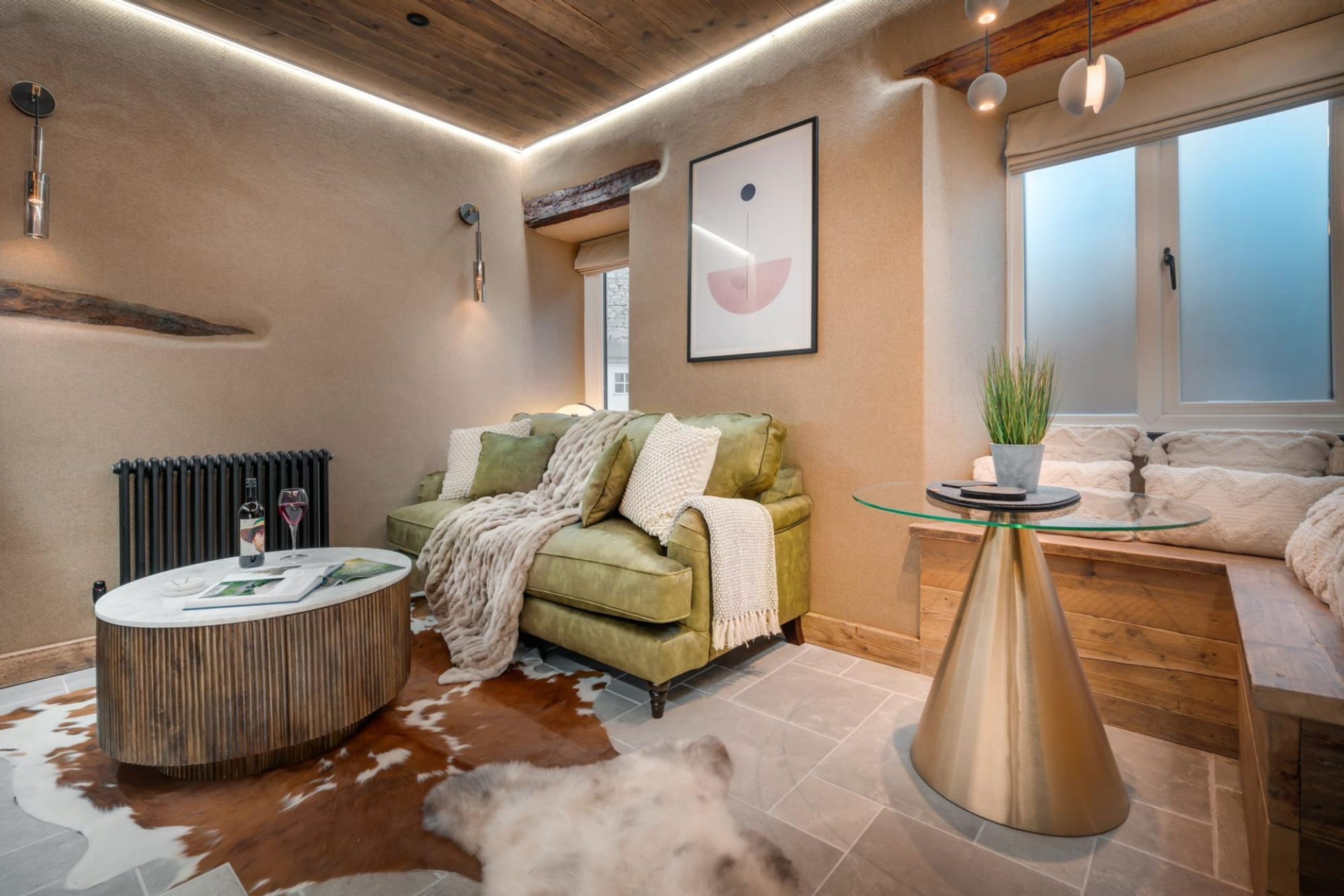 A modern living room with a green sofa, a round coffee table, and a glass-top side table.