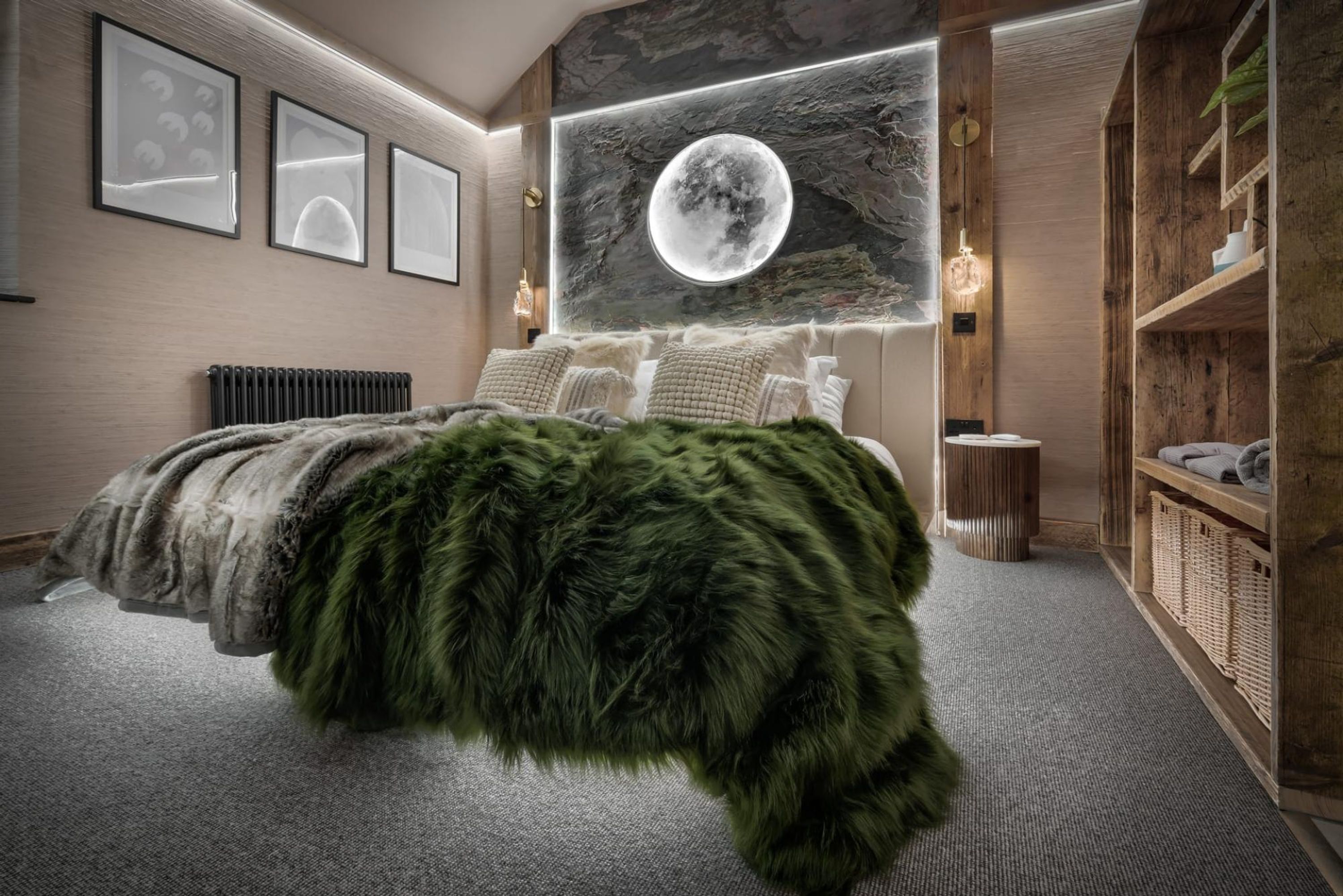 A bedroom with a large bed, a wall-mounted moon painting, and a wooden shelving unit.