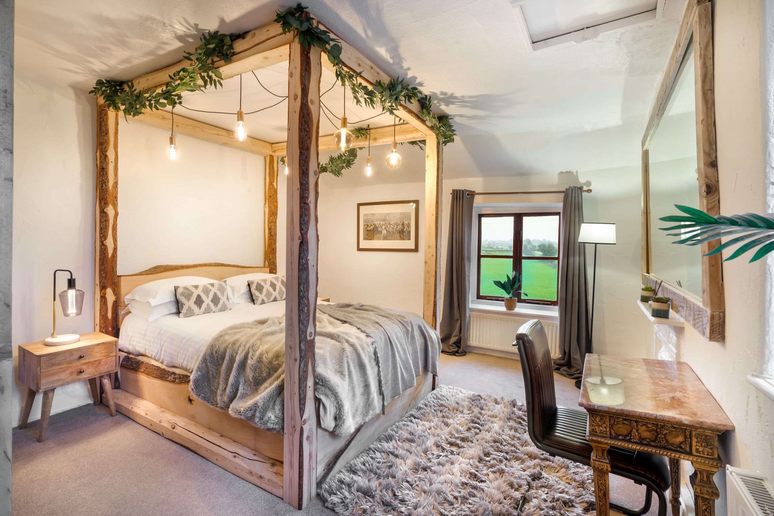 Een slaapkamer met een hemelbed, een bureau, een stoel en een raam met uitzicht op een groen veld.