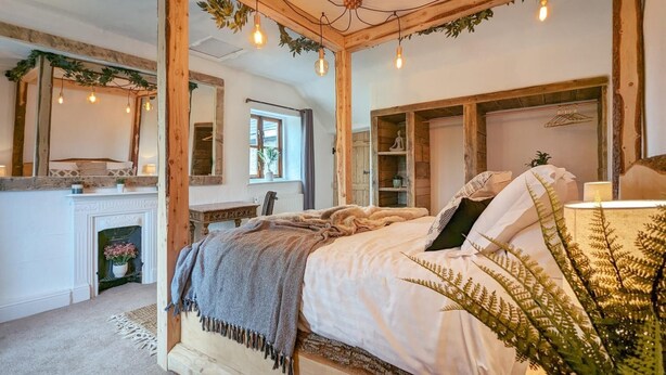 Um quarto aconchegante com uma cama de madeira com dossel, uma lareira e um espelho grande.