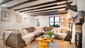 Uma sala de estar acolhedora com um sofá seccional, uma mesa de centro de madeira e uma lareira de pedra.