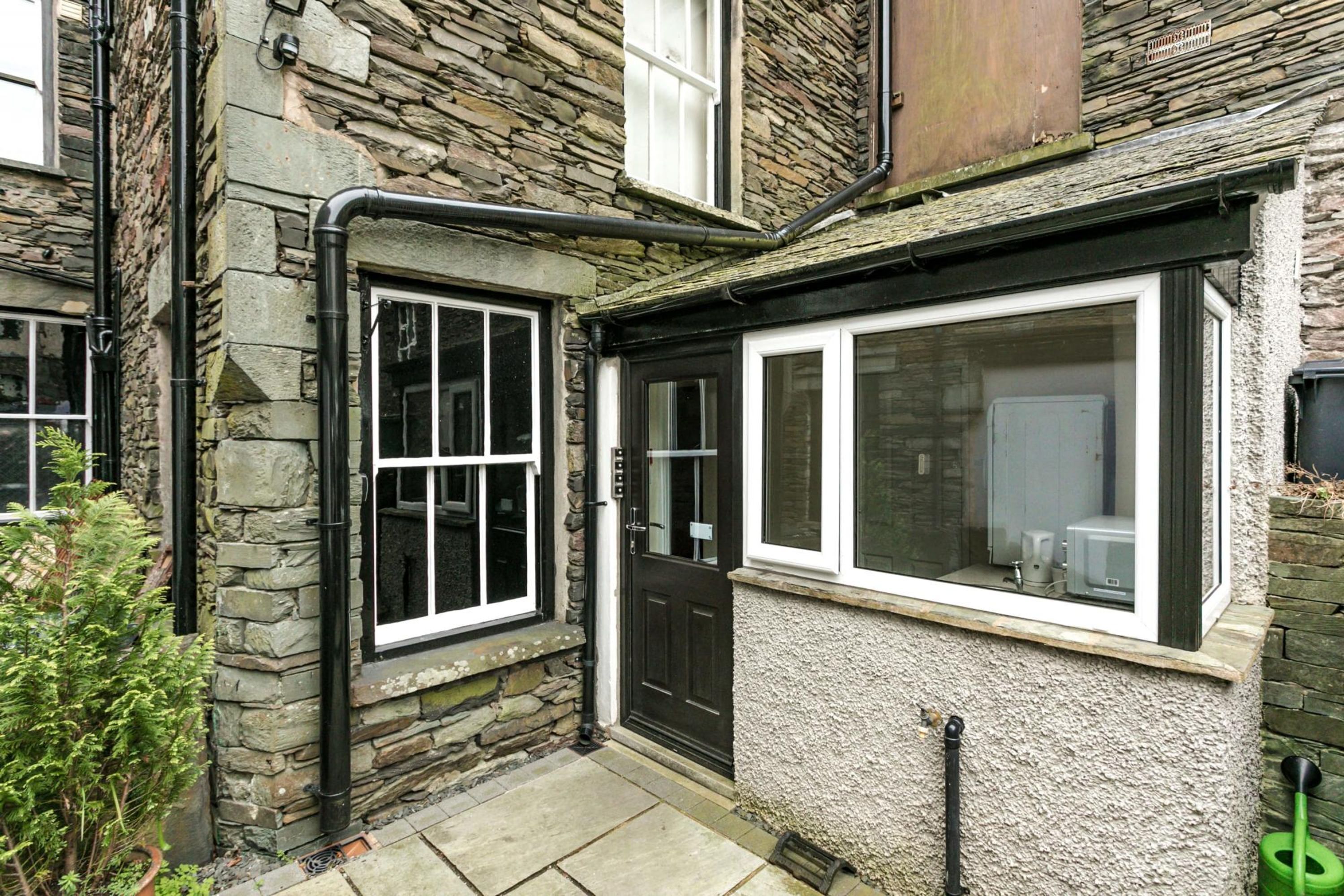 A stone house with a black door and white-framed windows.