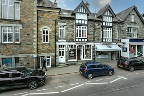 A street view with a building featuring a shop named "Ambleside Sheepskins" and a visible sign for "TO24". - Rohan Rise - Lake District Escape for Two (Ambleside)
