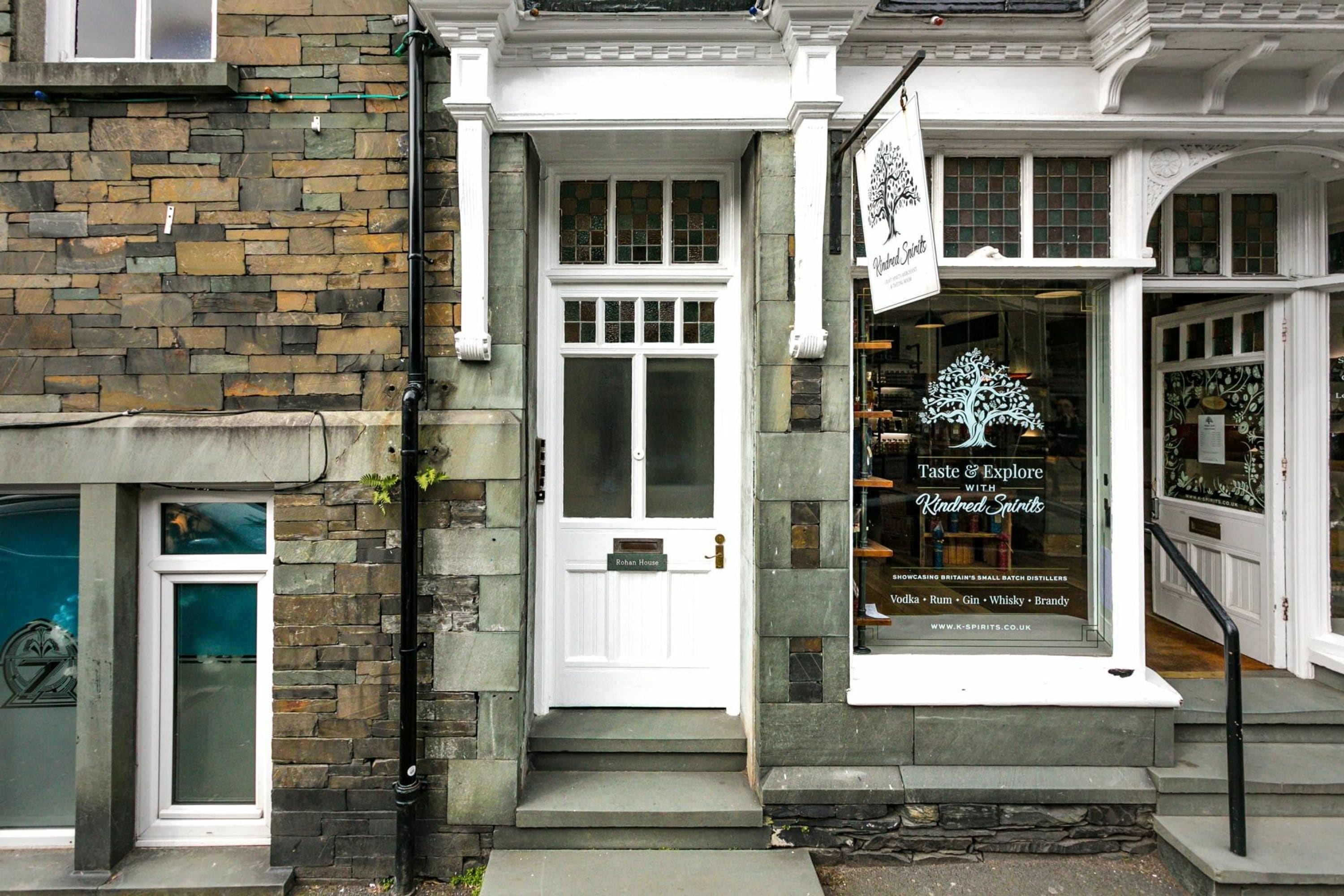 A building with a stone facade, a white door, and a sign advertising a distillery.