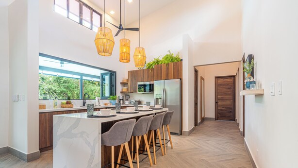 Une cuisine moderne dotée d’un grand îlot central, de tabourets de bar et d’un ventilateur de plafond.