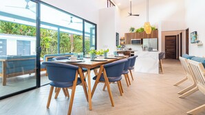Une cuisine moderne avec des meubles en bois, un four à micro-ondes et un coin repas comprenant une table en bois et des chaises bleues.