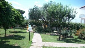 A garden with a pathway, trees, and a blue play structure.