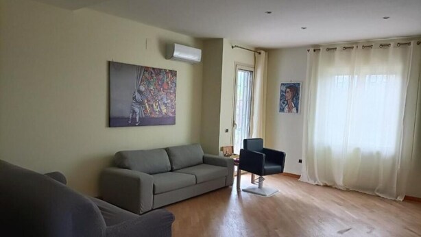 A living room with a grey sofa, a black chair, and a painting on the wall.