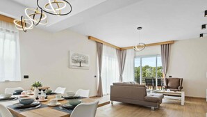 A modern living room with a dining area, featuring a sofa, a coffee table, and a dining table set for four. - Villa Palma - Seaside Luxury Villa for 6 Person (Pula)
