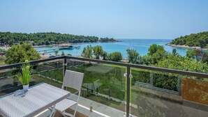 Un balcon avec une table et des chaises donnant sur une zone côtière, avec un ciel dégagé.