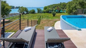 Un espace piscine comprenant deux chaises longues, un jacuzzi et une vue sur la mer.