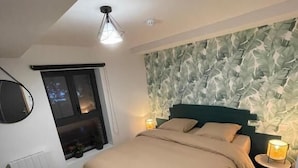 A bedroom with a bed, two bedside tables, a window, a radiator, and a ceiling light. - L'Auberge de papa (Auzouville-sur-Ry)