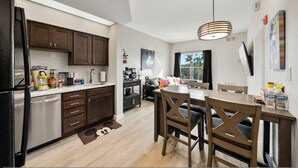 Eine moderne Küche mit dunklen Holzschränken, einem Edelstahlkühlschrank und einem Essbereich mit Holztisch und Stühlen.