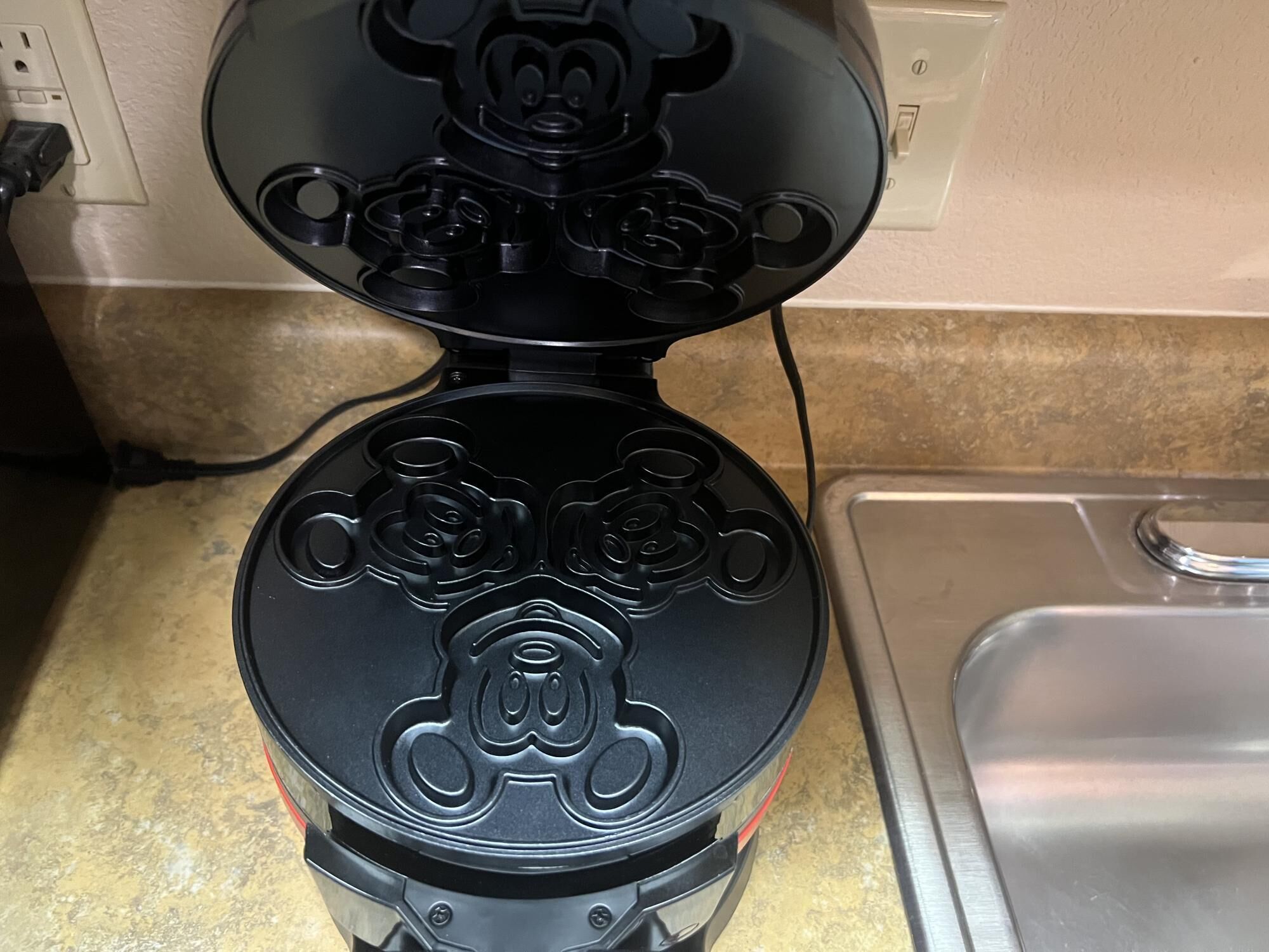 A black, two-tiered, stainless steel kitchen range hood with a vented top.