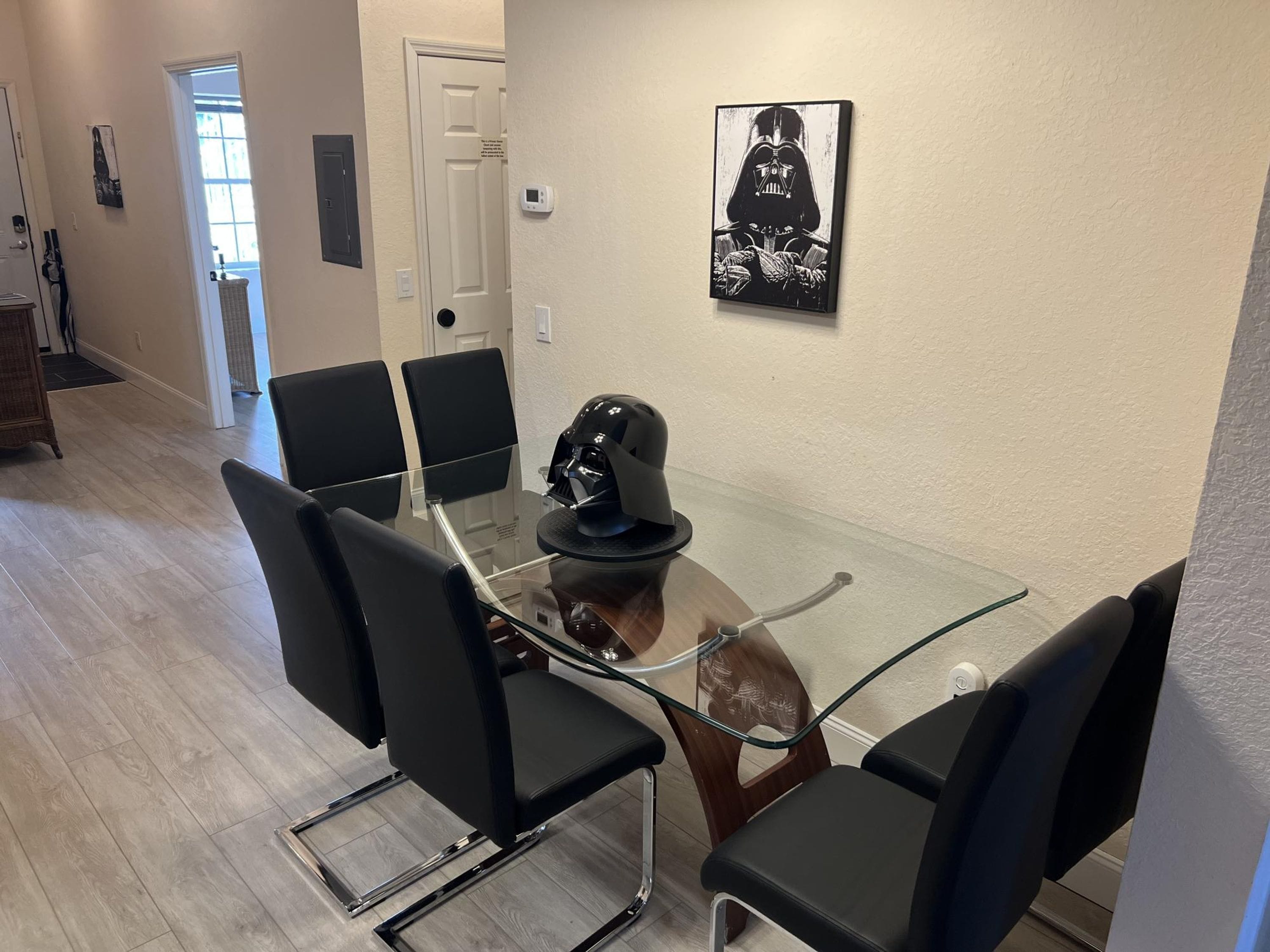 Une salle de conférence avec une table en verre, des chaises noires et une affiche de Dark Vador au mur.