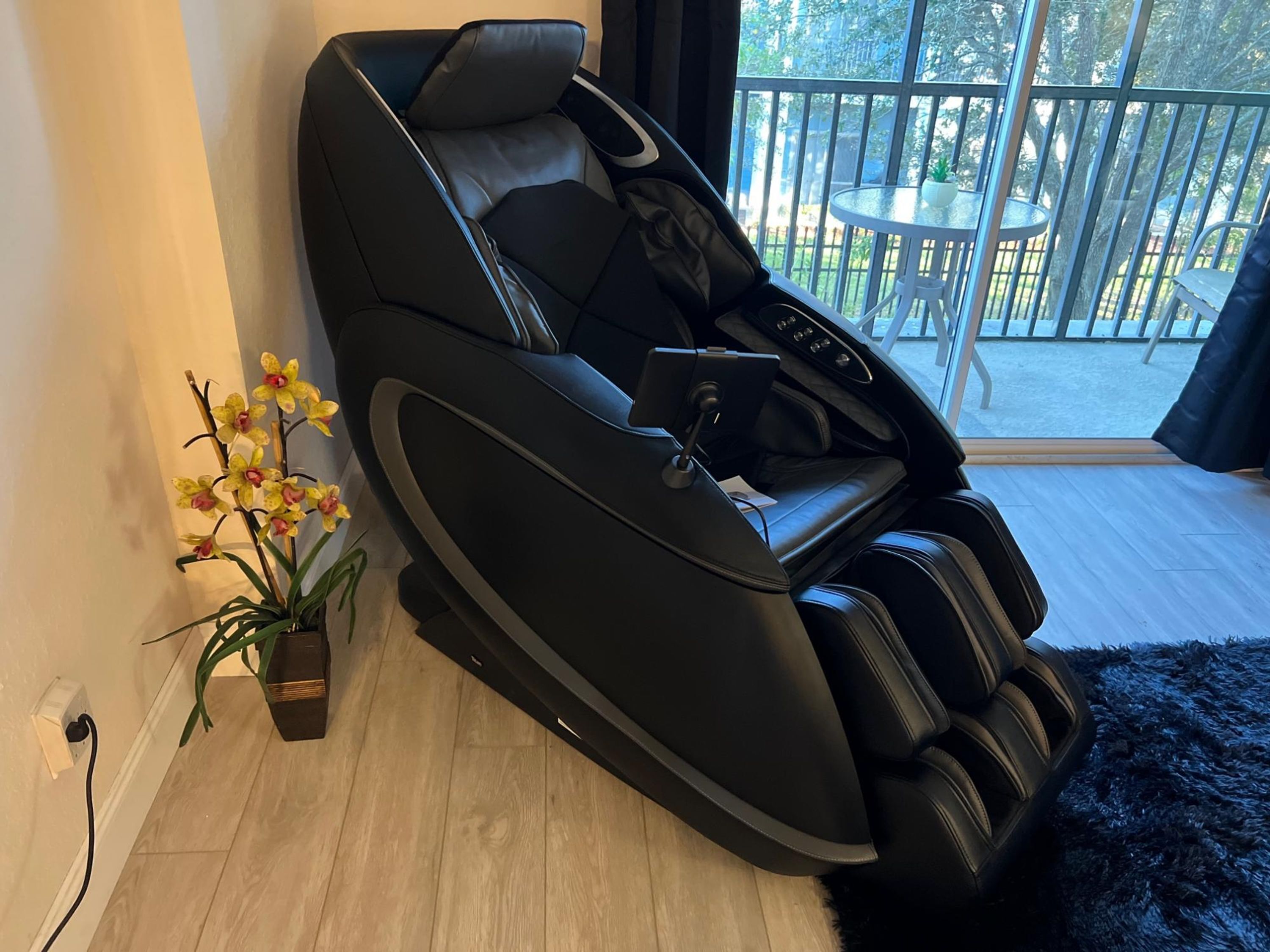 A massage chair in a room with a view of a balcony.