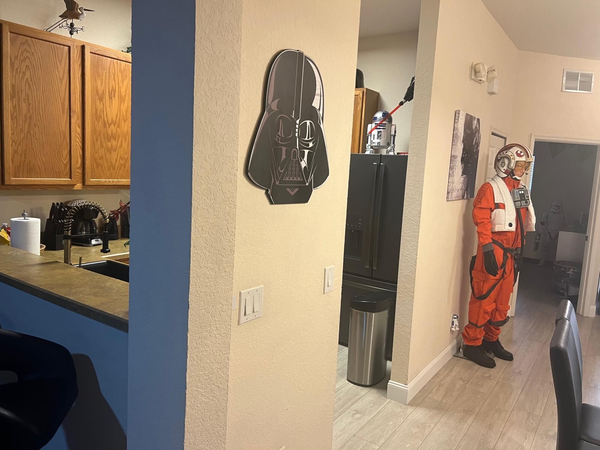Una cucina con mobili in legno, un frigorifero nero e una chitarra appesa al muro.