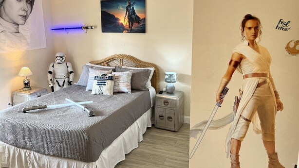 A bedroom with a bed, pillows, a Star Wars poster, a Star Wars-themed wall decal, and a Star Wars figurine.