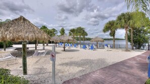 A beach with thatched umbrellas, blue lounge chairs, and a wooden walkway. - Disney Area Vacation Kissimmee (Davenport)