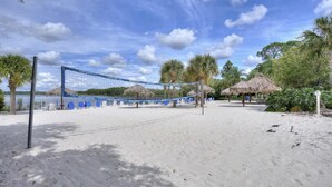 A beach volleyball court with net, blue lounge chairs, and palm trees. - Disney Area Vacation Kissimmee (Davenport)