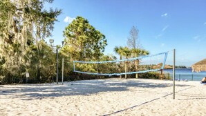 A beach volleyball court with a net, surrounded by sand and trees. - Disney Area Grnd Floor Park Free (Davenport)