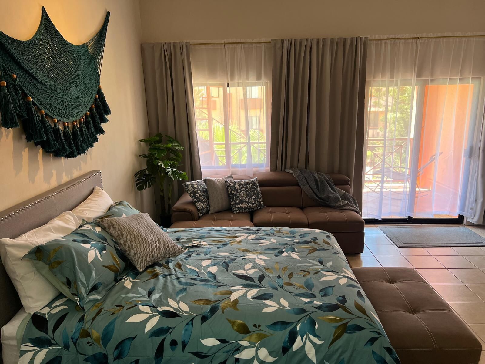 Une chambre à coucher avec un lit, un canapé et une grande fenêtre avec des rideaux.