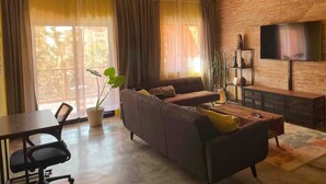 Una sala de estar con sofá, televisión y comedor con mesa y sillas.