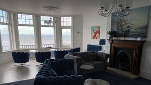 A living room with a view of the sea, a fireplace, and modern furniture.