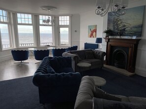 Una sala de estar con vista al mar, chimenea y muebles modernos.