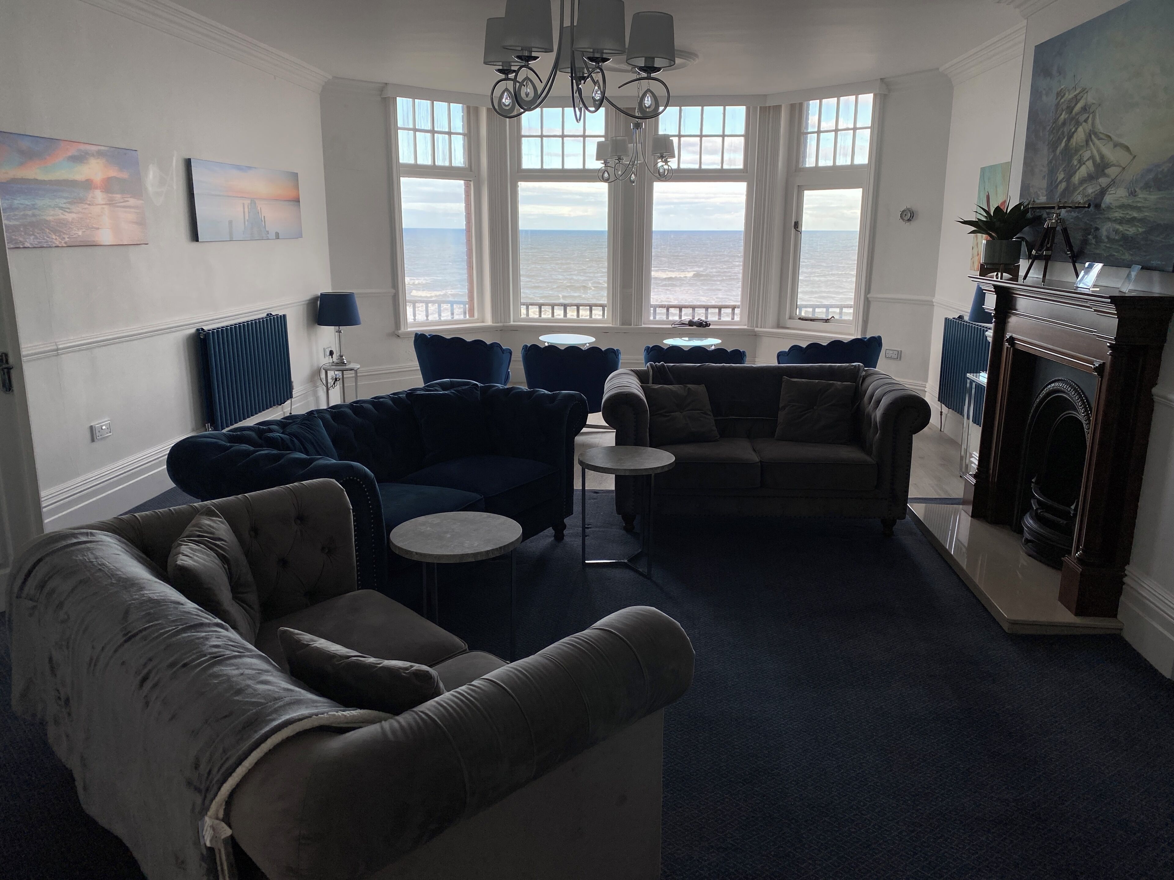 Een woonkamer met uitzicht op zee, een open haard en een kroonluchter.