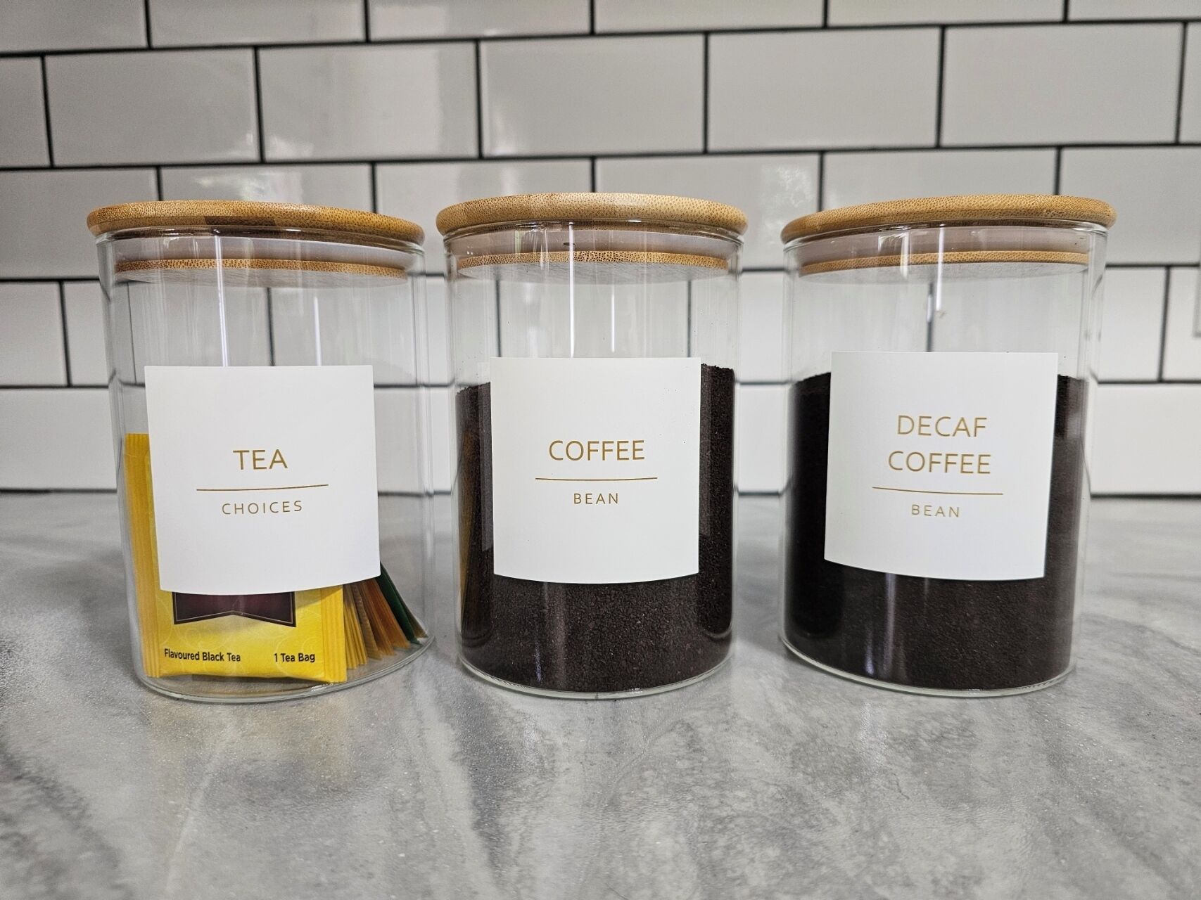 Trois récipients en verre, chacun portant une étiquette, sont posés sur un comptoir.