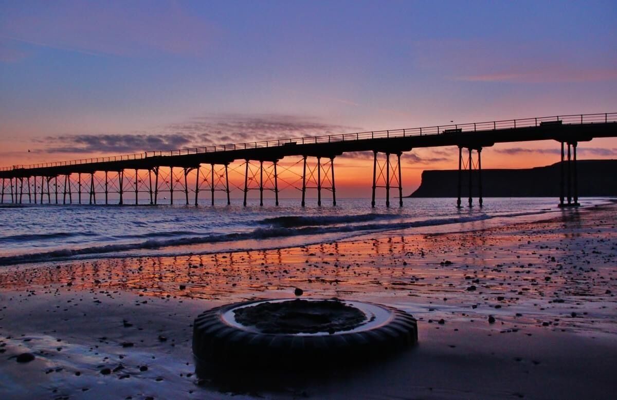 A pier extending into the water with a sunset in the background.