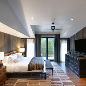 Relax in comfort with a large bed against a wall, ceiling fan above, and a flat-screen TV mounted on the wall.
